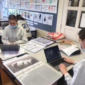 Two VCE Visual Arts students sitting at desks working on their Visual Arts Folios.